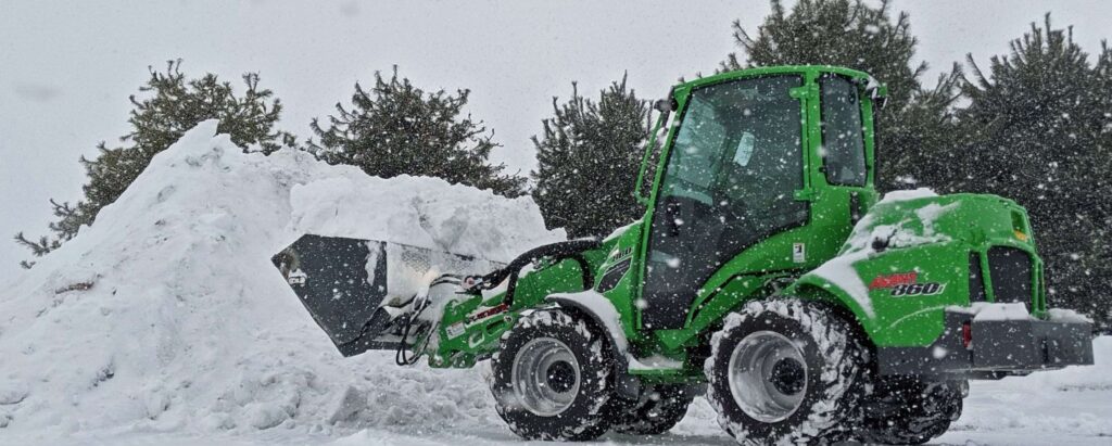 a green snow plowing machine cleaning snow