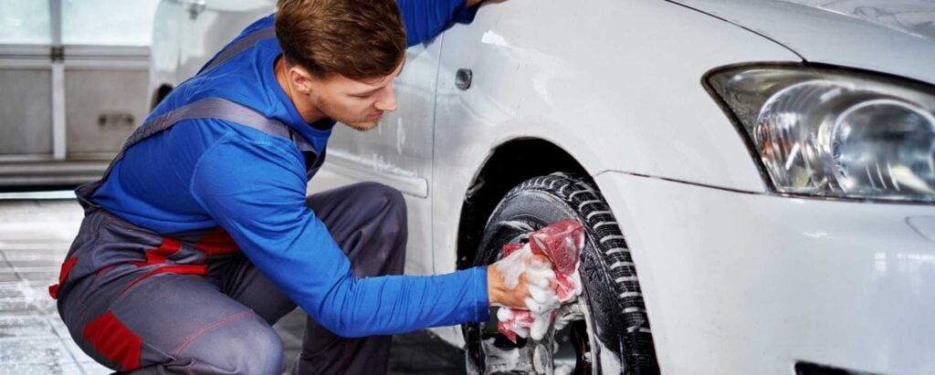 a man in a uniform washing tires