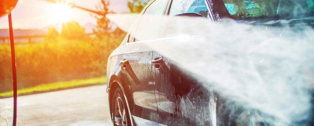 a person pressure washing a car