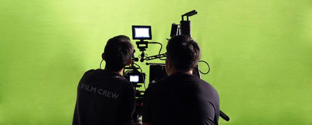 two camera men in front of a green screen