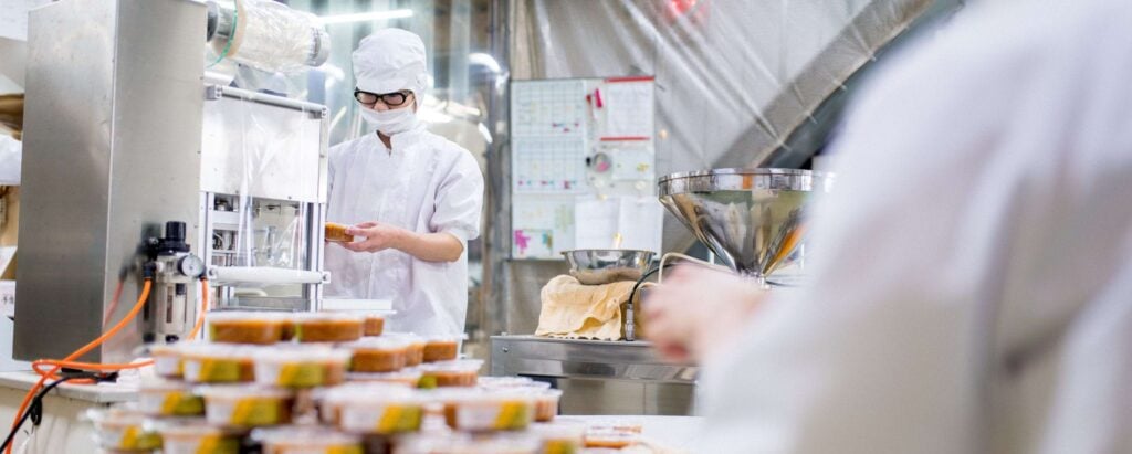people working on an assembly line, packing food