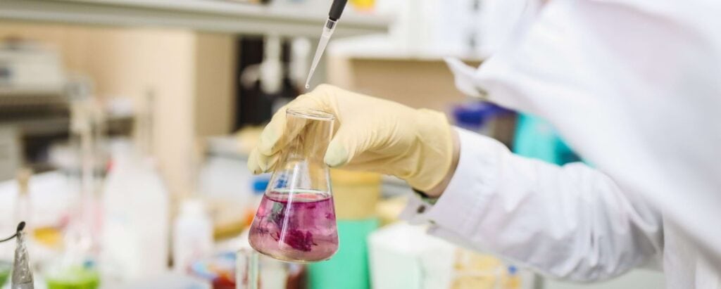 a person mixing chemicals in a glass container