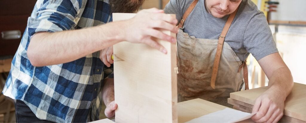 two men assembling a handcrafted wooden item