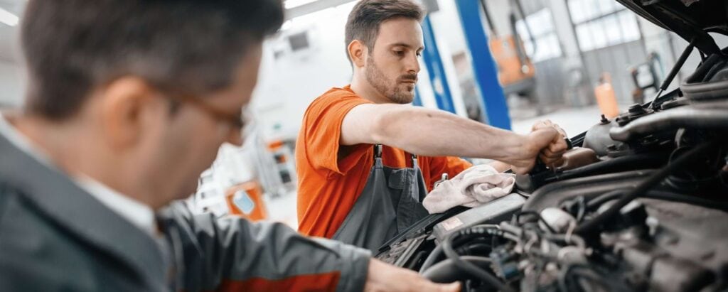 two men working on the engine of a car