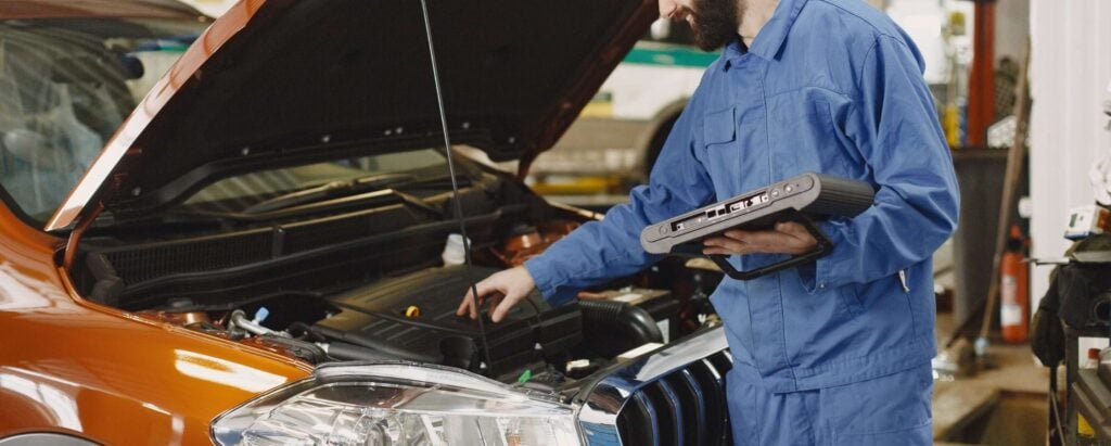 a man in a blue suit working on fixing a car