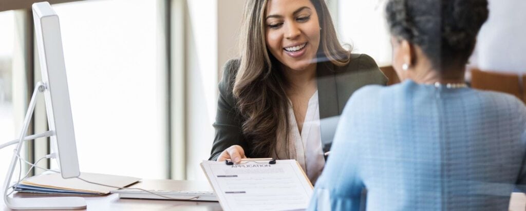 an investment banker handing over an application form to a customer