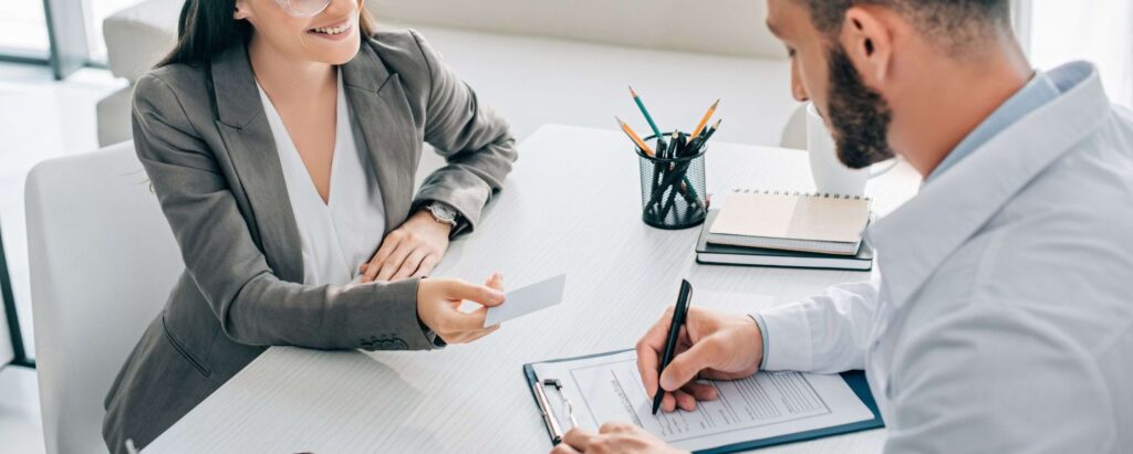 a woman handing a card to a man who's signing a form