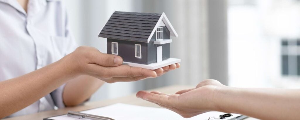 a woman handing over a tiny house model to another person