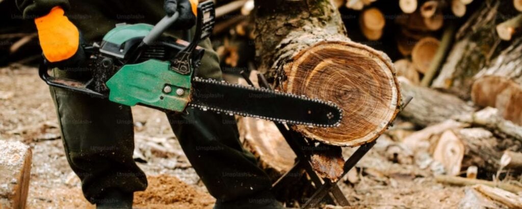 logging worker cutting wood