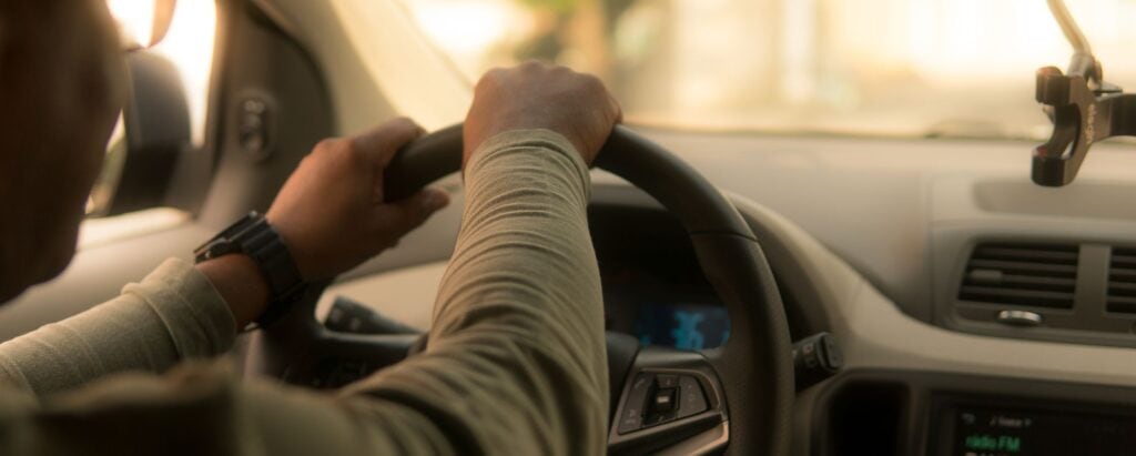 Person driving car - getting paid to drive - holding steering wheel