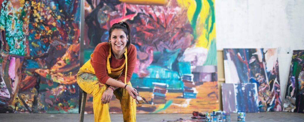 Woman artist sitting in an art studio with paint brushes in her hands