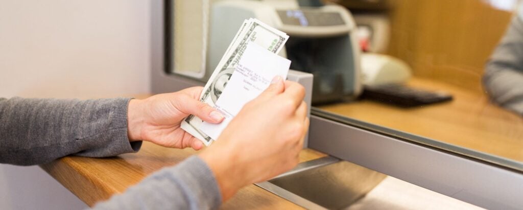 A person receiving the money from a cashing store counter