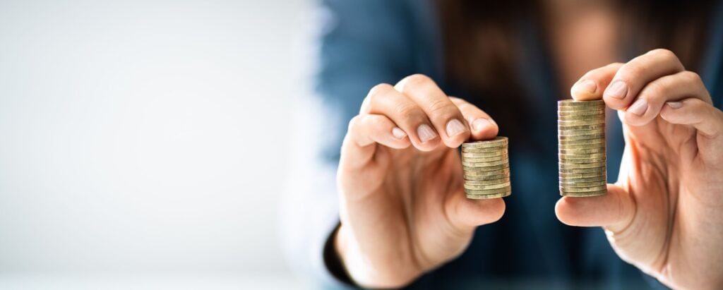 person comparing two piles of coins in his hands