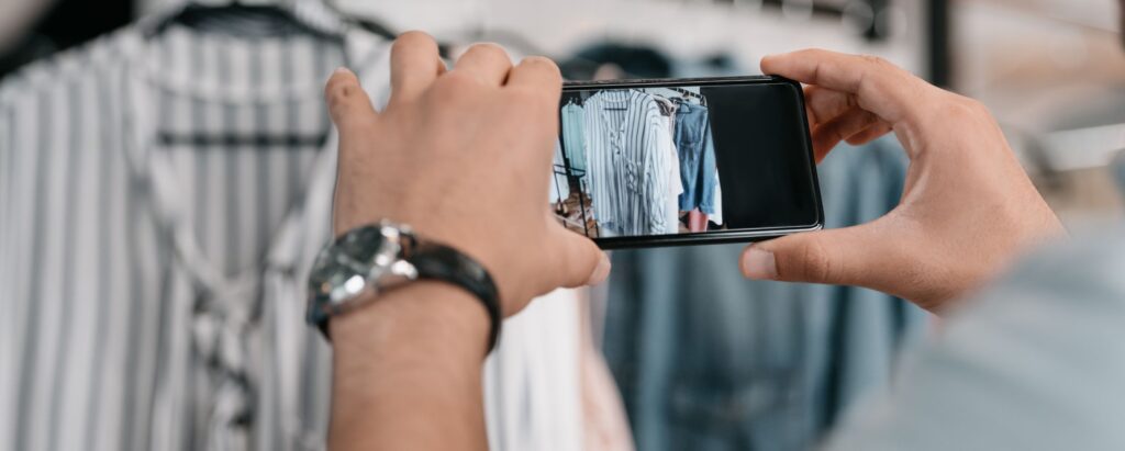 A person is taking photos of clothes with a mobile phone