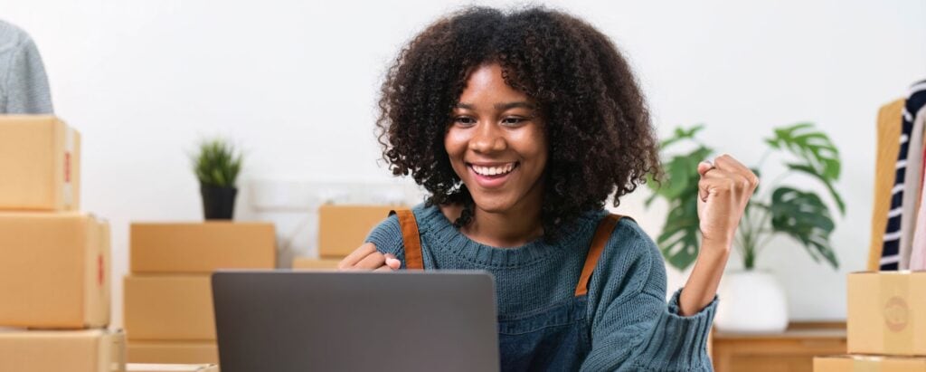 A woman is celebrating a successful sale in front of the computer